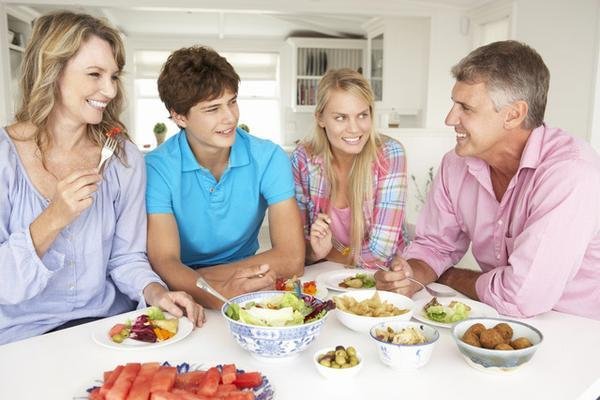 A Christian family with two teenagers sharing a meal together at the table